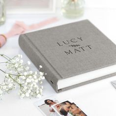 a wedding album is sitting on a table next to some flowers and other personalized items