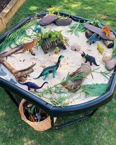 an outdoor sand and water play table with dinosaurs in it