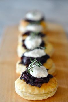 small pastries are lined up on a wooden board