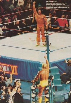 a man standing on top of a wrestling ring in front of a crowd with his arms up