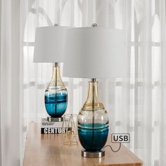 two blue vases sitting on top of a wooden table next to a white lamp