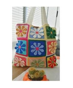 a colorful crocheted bag sitting on top of a table next to a cactus