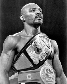 a black and white photo of a man wearing a wrestling belt