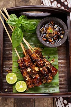 grilled meat and vegetables on a plate with chopsticks, garnished with green leaves