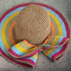 a multicolored hat with a large bow on it's brim sits on the ground