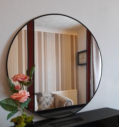 a mirror that is sitting on top of a dresser next to a vase with flowers