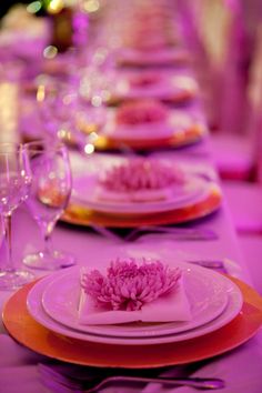 the table is set with pink plates and place settings