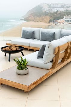 a couch and table sitting on top of a tiled floor next to a balcony overlooking the ocean