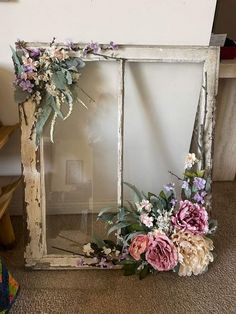 an old window is decorated with flowers and greenery to look like it has been placed on the floor