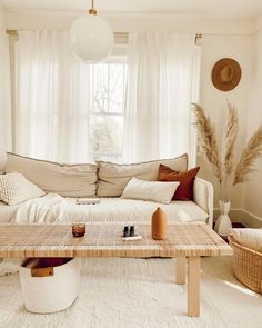 a living room filled with furniture and pillows on top of a table in front of a window