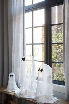 three ghost - like heads are sitting on a window sill in front of a curtained window