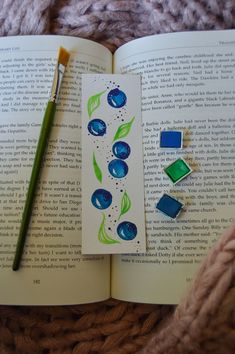 an open book with blue and green designs on it next to a pencil, eraser and crayons