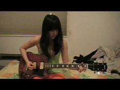 a woman sitting on top of a bed holding an electric guitar