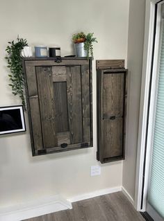 two wooden cupboards sitting next to each other in a room with wood floors and white walls