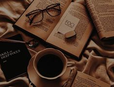 an open book, eyeglasses, and cup of coffee sit on a bed