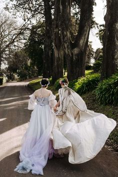 two women in white dresses walking down the road