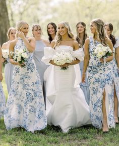 a group of women standing next to each other wearing dresses and holding bouquets in their hands