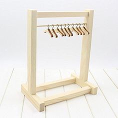 a wooden rack with clothes hanging from it's hooks on a white wall background