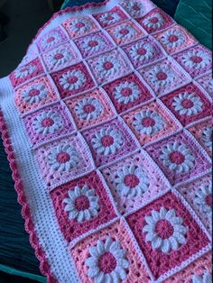 a pink and white crocheted blanket sitting on top of a bed