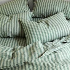 an unmade bed with green and white striped sheets