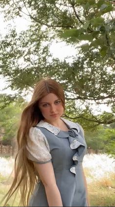 a woman with long hair standing under a tree