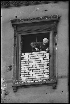 black and white photograph of man in window with bricks