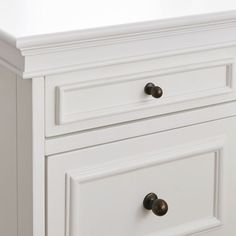 a white dresser with three drawers and two knobs