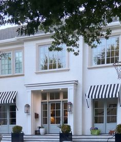 a large white house with black and white striped awnings on the front door