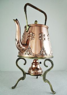 an antique copper tea pot on a stand