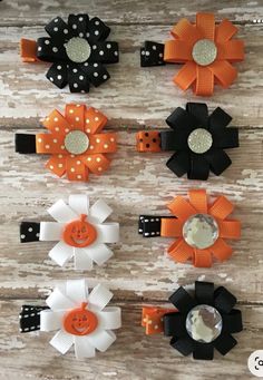 six orange, black and white hair bows with polka dots on them sitting on a wooden surface