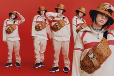 three women in matching outfits with hats and purses on their shoulders, standing against a red background