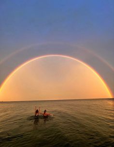two people in the water under a rainbow