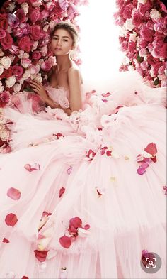 a woman in a pink dress surrounded by flowers with petals all over her body and face