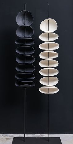 three black and white plates on stands against a dark wall, each with different shapes