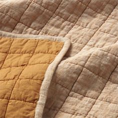 an orange and yellow quilted bed spread on top of a white pillow coverlet