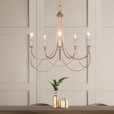 a chandelier hanging from the ceiling over a dining room table with candles on it