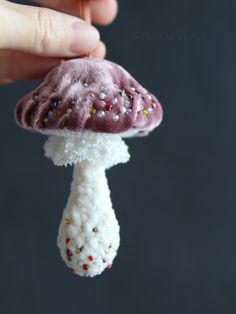 a hand is holding a tiny mushroom ornament