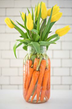 a jar filled with carrots and yellow flowers