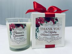 a white candle with a red ribbon around it and a thank you card next to it