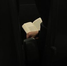 a person reading a book while sitting in a chair with their hands on an open book