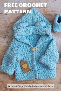 a blue knitted jacket and booties on a wooden floor with a brown teddy bear