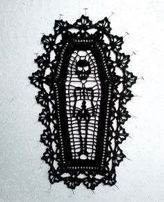 an intricately designed piece of art hanging on the side of a wall with black thread