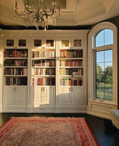 a living room filled with lots of books on top of a book shelf next to a window