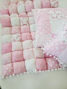 a pink and white patchwork quilt with polka dot pillows on it, along with two teddy bears