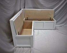 two white wooden boxes sitting next to each other on a sheeted surface with the lid open