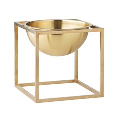 a golden metal bowl sitting on top of a wooden stand