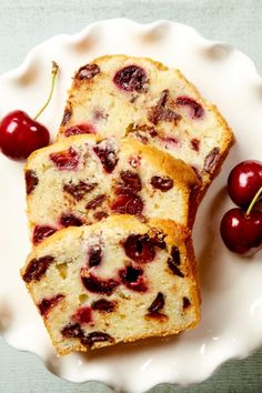 two slices of cherry bread on a plate with cherries next to it and one slice cut in half