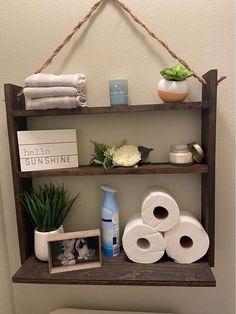 a bathroom shelf filled with toilet paper, plants and other items on top of it