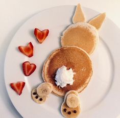 some pancakes and strawberries are on a white plate with the shape of an animal