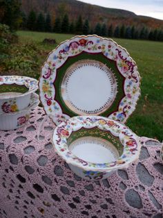 three plates and two bowls on a table with a pink doily in the foreground